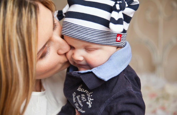 Eine Mutter küsst ihr Baby und kann dadurch Herpes übertragen